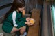 A woman sitting on a bench holding a bowl of food.