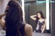 A woman in a black lingerie looking at herself in the mirror.