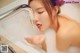 A woman is taking a bath in a bathtub with foam.