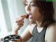 A woman eating a chocolate cookie with her mouth open.