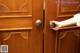 A person is opening a wooden door with a brass knob.